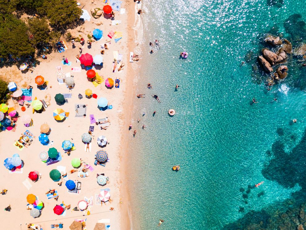 Image showing an aerial view of the white beach at Costa Smeralda in Sardinia, packed with beach umbrellas and tourists.